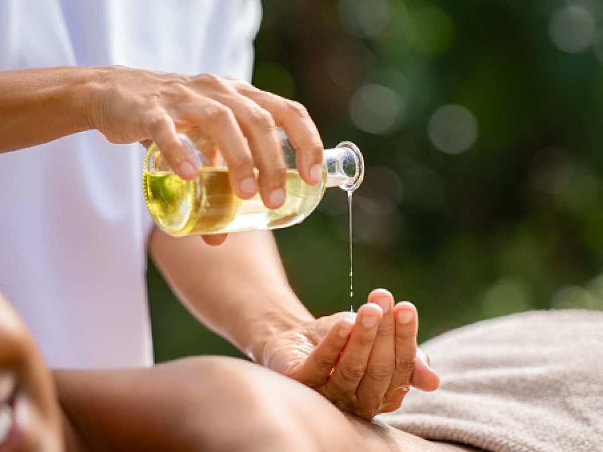 Closeup of masseuse hands pouring aroma oil on woman back. Woman prepare to do oriental spa massage for relaxing treatment. Therapist doing aromatherapy oil massage on girl body. Body care concept.